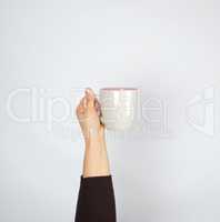 gray ceramic cup in female hand on a white background, hand rais