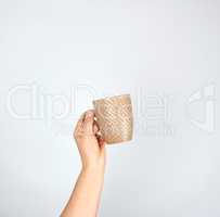 brown ceramic cup in a female hand on a white background