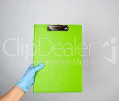 female hand with blue medical glove holding a green tablet for c