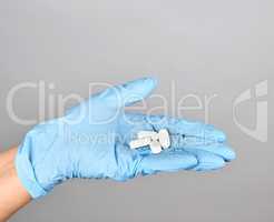 blue sterile gloved hand holding white pills