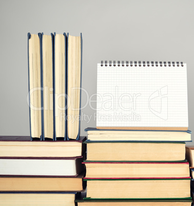 open blank notebook is standing on the stack of books