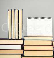 open blank notebook is standing on the stack of books