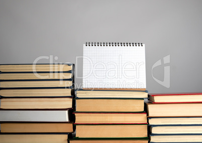 open blank notebook is standing on the stack of books