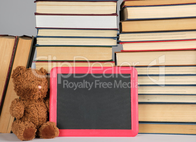 brown teddy bear and empty black board in red frame on the backg