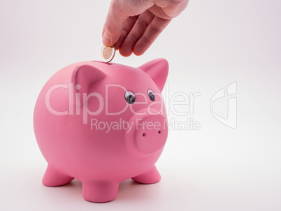 Hand wirft Euromünze in pinkes Sparschwein