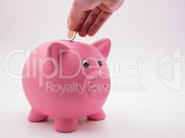 Hand wirft Euromünze in pinkes Sparschwein