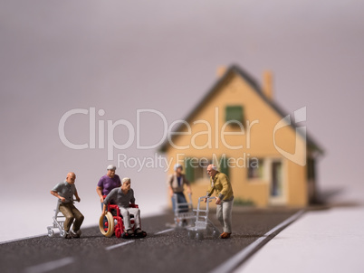 Miniatur Senioren mit Rollstuhl und Rollatoren auf Strasse