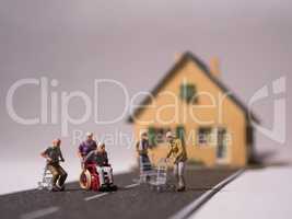 Miniatur Senioren mit Rollstuhl und Rollatoren auf Strasse