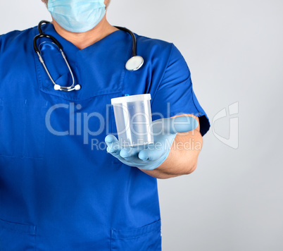 doctor in blue uniform and latex gloves is holding an empty plas