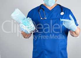 doctor in uniform and in blue latex gloves keeps sterile masks