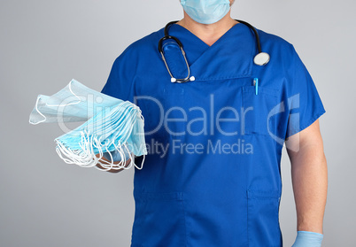 doctor in uniform and in blue latex gloves keeps sterile masks