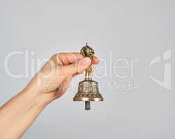 female hand holding a bronze bell for alternative medicine