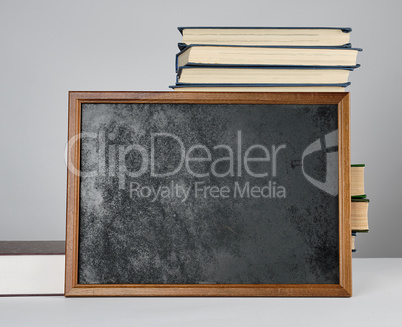 empty black chalk drawing frame and stack of books