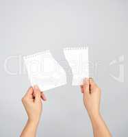 two hands hold a torn piece of paper on a gray background