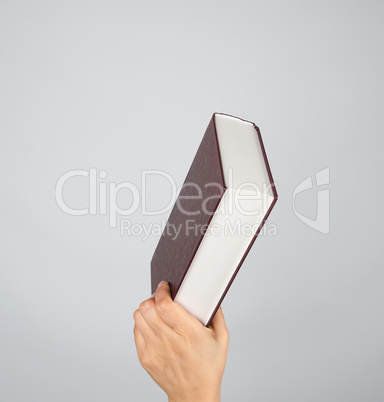 hand holds a closed book in hardcover