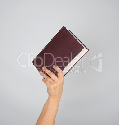 hand holds a closed book in hardcover