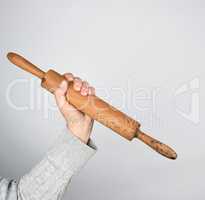 hand holding a wooden rolling pin