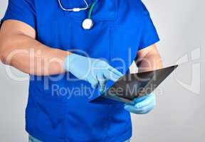 doctor in blue uniform and sterile latex gloves holds and examin