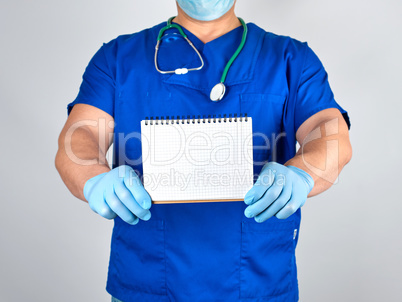 doctor in blue uniform and sterile latex gloves holding open bla