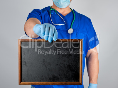 doctor in blue uniform and sterile latex gloves holding a wooden