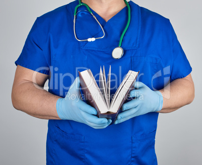 doctor in blue uniform holds an open book in his hands