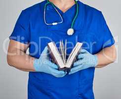 doctor in blue uniform holds an open book in his hands