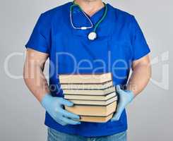 doctor in blue uniform and sterile latex gloves holds a stack of