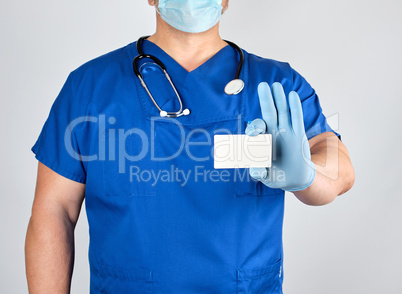 doctor in sterile latex gloves and blue uniform holds a blank wh