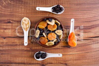 Mix of dried fruits in a wooden bowl over a rustic table
