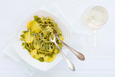 Linguine pasta with pesto genovese, potatoes and white wine glas