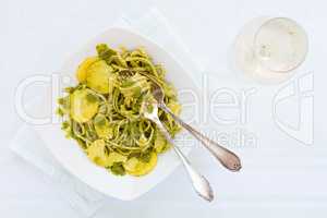 Linguine pasta with pesto genovese, potatoes and white wine glas