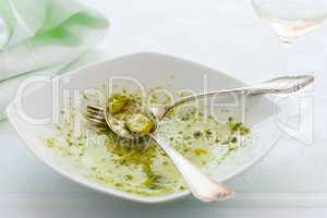 Closeup of eaten linguine pasta plate with pesto genovese and po