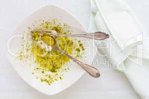 Closeup of eaten linguine pasta plate with pesto genovese, cutle