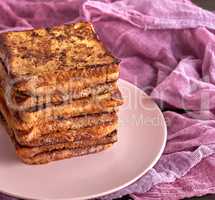 stack of square pieces of fried bread slices on a pink ceramic r