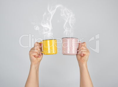 two raised hands up with ceramic cups, thick steam comes out of