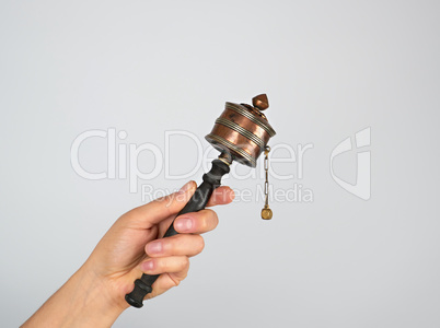 copper prayer drum on a stick in a female hand