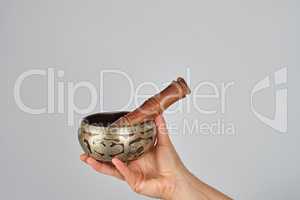 copper singing bowl and wooden stick in female hand