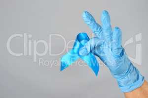hand in blue latex glove holding a blue ribbon