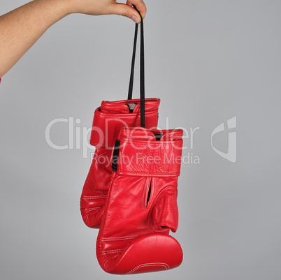 pair of red leather boxing gloves hang on a string
