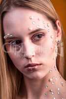 Girl with white and pearl rhinestones on her face.