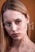 Girl with white and pearl rhinestones on her face.