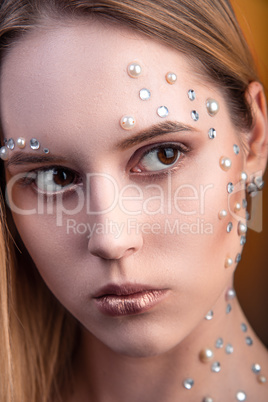 Girl with white and pearl rhinestones on her face.