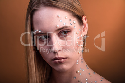 Girl with white and pearl rhinestones on her face.