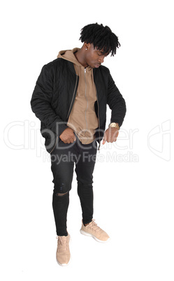 Black man standing in studio looking at his watch