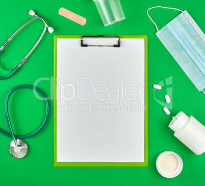 paper holder with empty white sheets, medical stethoscope, pills