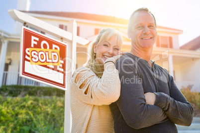 Attractive Middle-aged Couple In Front House and Sold Sign