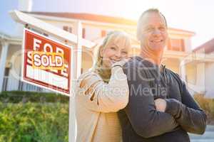 Attractive Middle-aged Couple In Front House and Sold Sign
