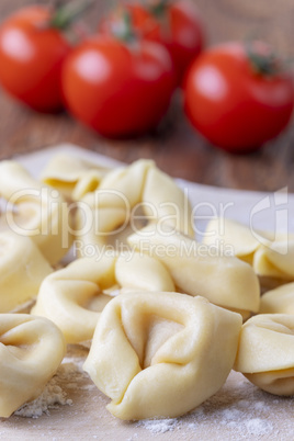 Rohe Tortellini auf Holz mit Tomaten