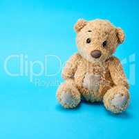 very old brown teddy bear on a blue  background