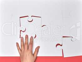 female hand puts white big puzzles on a pink background